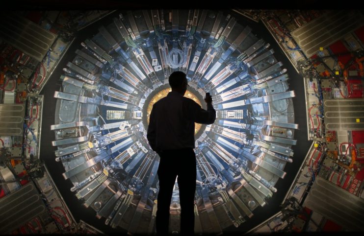 LONDON, ENGLAND - NOVEMBER 12: A visitor takes a phone photograph of a large back lit image of the Large Hadron Collider (LHC) at the Science Museum's 'Collider' exhibition on November 12, 2013 in London, England. At the exhibition, which opens to the public on November 13, 2013 visitors will see a theatre, video and sound art installation and artefacts from the LHC, providing a behind-the-scenes look at the CERN particle physics laboratory in Geneva. It touches on the discovery of the Higgs boson, or God particle, the realisation of scientist Peter Higgs theory. (Photo by Peter Macdiarmid/Getty Images)