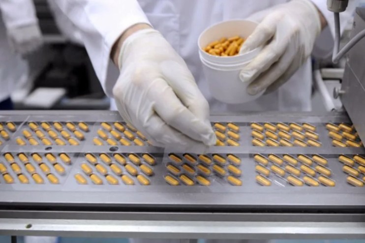 Worker at a medicine factory placing pills into viles