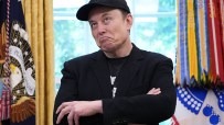 Elon Musk speaking at a tech conference, wearing a suit, with a futuristic backdrop highlighting space exploration themes