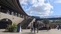 Kings Cross Coal Drops Yard bustling with shoppers and visitors amidst modern architecture and vibrant store displays