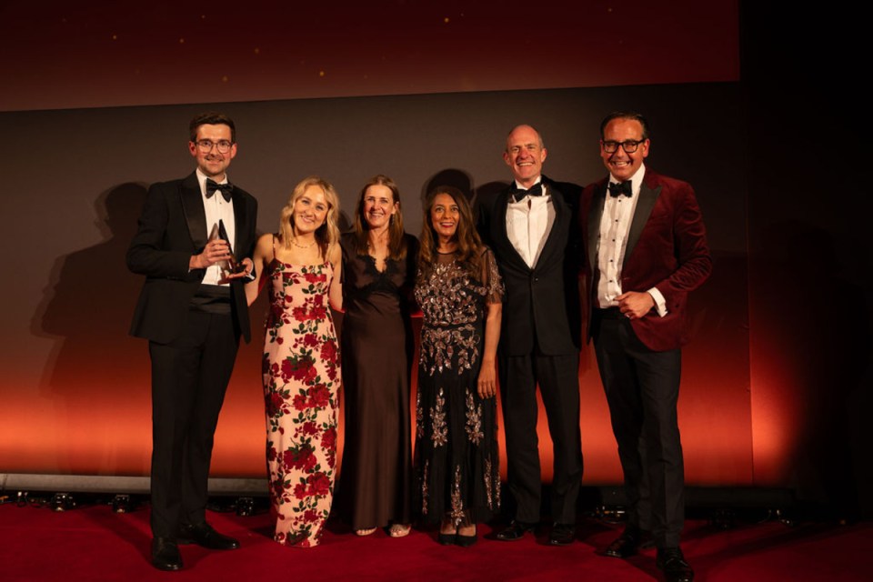 Shawbrook Bank celebrates win at CityAM Awards with team on stage holding trophy in formal attire