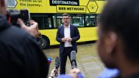 Andy Burnham discussing Bee Network devolution plan with city skyline in background