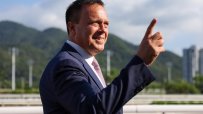 Caspar Fownes confidently poses at a racing event, showcasing his expertise and leadership in the horse racing industry.