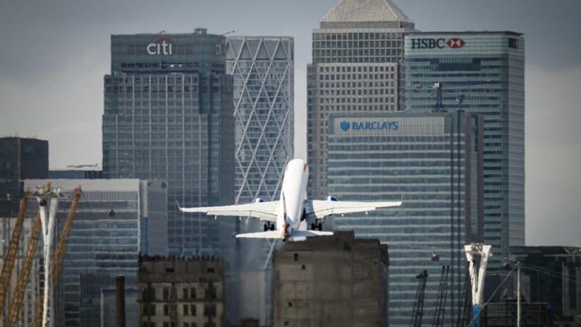 London City Airport terminal bustling with travelers and staff, showcasing modern architecture and vibrant city backdrop.
