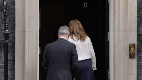 Keir Starmer standing near Number 10 Downing Street discussing political matters with media presence in the background