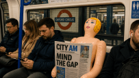 Abandoned doll on London Tube seat holding CityAM newspaper, capturing urban life and public transport atmosphere