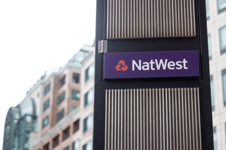 NatWest sign on a dark pillar with vertical slats, set against a blurred background of a modern office building