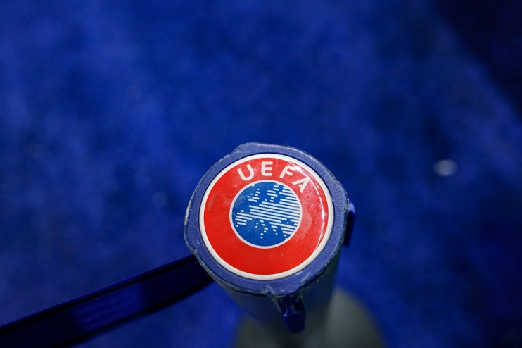 Close-up of a blue and red UEFA logo on a sports equipment handle against a blurred blue background