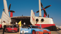 Luxury sports cars lined up at the start of the Gumball 3000 rally, showcasing sleek designs and vibrant colors.