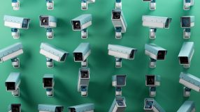 Multiple CCTV security cameras in light blue and white against a green background, emphasizing surveillance and monitoring.