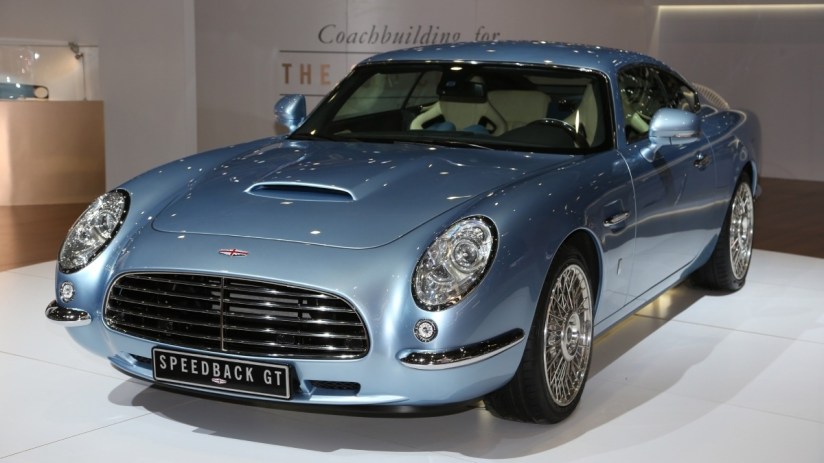 Light blue David Brown Automotive Speedback GT sports car, front 3/4 view, at an auto show display.