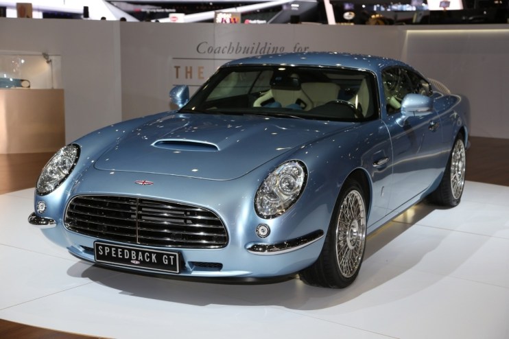 Light blue David Brown Automotive Speedback GT sports car, front 3/4 view, at an auto show display.