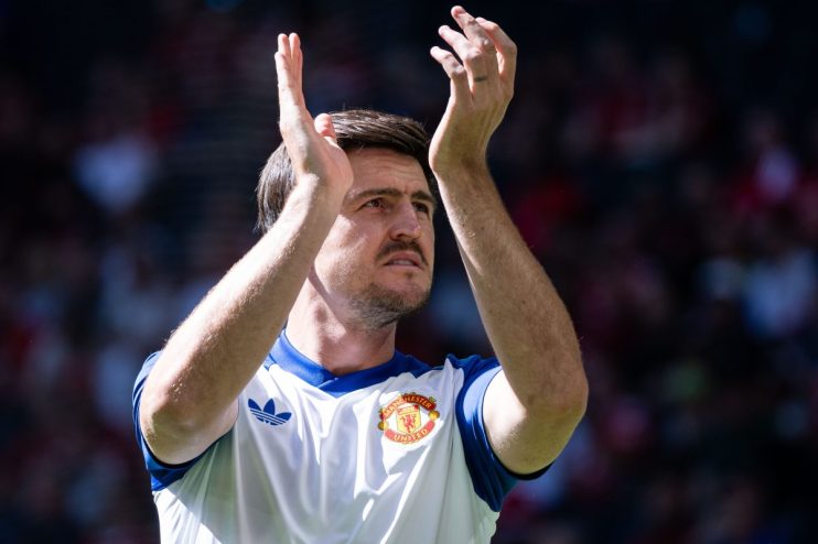 Harry Maguire in a Manchester United jersey, clapping during a match, looking up.