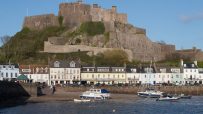 Mont Orgueil Castle overlooking Gorey Harbour with boats and waterfront buildings in Jersey, Channel Islands.
