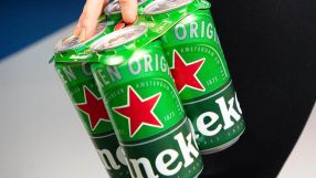 Hand holding a 4-pack of green Heineken beer cans with red stars and white lettering