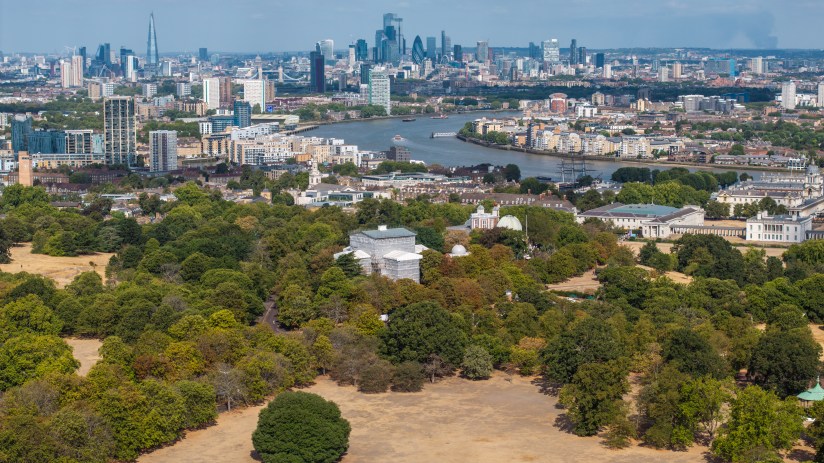 London cityscape from Primrose Hill showing dry, brown grass during drought with River Thames and skyscrapers